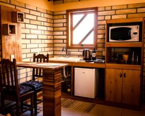 a kitchen with a table and a sink and a microwave at Chalé Girassol in Praia Grande