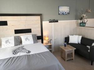 Appartement Duinzee Texel في دي كوخ: غرفة نوم بسرير واريكة