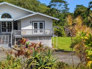 ein weißes Haus mit einer Veranda und einigen Pflanzen in der Unterkunft Hilo Luxury Suite in Hilo