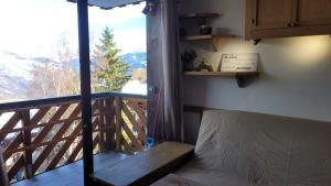 Habitación con cama y balcón con vistas. en Studio Plagne Montalbert Départ Skis aux pieds, en Montalbert