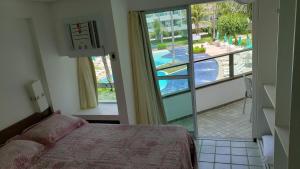 une chambre avec un lit et une vue sur une piscine dans l'établissement Ancorar Resort Frente Mar - Flat 6103, à Porto de Galinhas