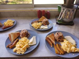4 assiettes d'aliments pour petit-déjeuner sur une table dans l'établissement Hotel Campestre Arenal, à Fortuna