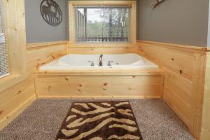 La salle de bains est pourvue d'une baignoire et d'une fenêtre. dans l'établissement Deer Pass Lodge, à Pigeon Forge 20 autres photos