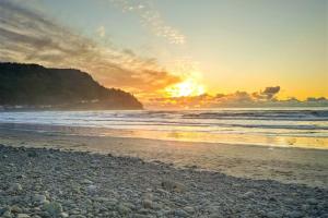a sunset on a beach with the ocean at Cozy Seaside Bungalow, Brand New Hot Tub, Fast WiFi & W&D - Walk to the Beach in Seaside