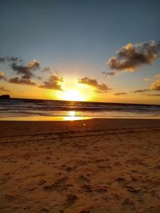 una puesta de sol en una playa con el océano en Camp NATURE, en Bli Bli