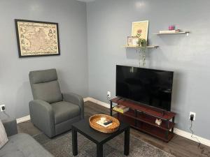a living room with a chair and a flat screen tv at Your cozy comfy rental in Cedar Manor