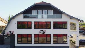 Cette grande maison blanche est dotée de fenêtres rouges. dans l'établissement Pálya Hotel, à Gheorgheni