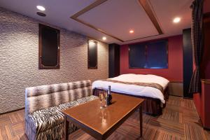a room with a bed and a couch and a table at ホテル ドルフィンリゾート 犬山 -大人専用- in Kakamigahara