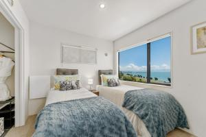 two beds in a bedroom with a large window at Ocean Spa Views in Nelson