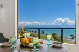 uma mesa com um prato de comida e uma garrafa de vinho em Ocean Spa Views em Nelson