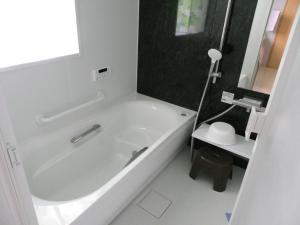 a white bathroom with a tub and a sink at Guest House Miyakojima in Miyako-jima
