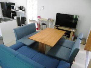 a living room with a blue couch and a wooden table at Guest House Miyakojima in Miyako-jima