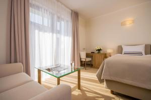 ヤロスワビエツにあるHotel Szlak Bursztynowyのベッドとガラスのテーブルが備わるホテルルームです。
