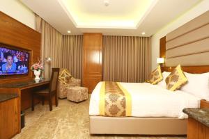 Habitación de hotel con cama, escritorio y TV. en Marino Royal Hotel en Dhaka