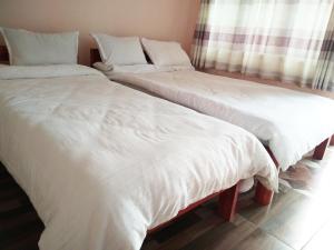 Duas camas num quarto com lençóis e almofadas brancos em Paramount guest house em Pokhara