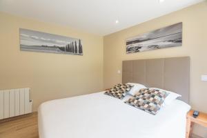 ein Schlafzimmer mit einem weißen Bett mit zwei Kissen in der Unterkunft Hôtel Le Printemps in Saint-Georges-de-Didonne