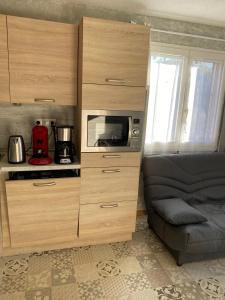 Armario de madera grande con microondas y sofá en Embrun - Appartement 4/6 personnes avec extérieurs en Embrun