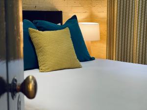 a bed with blue and yellow pillows and a lamp at The Shopkeepers Quarters in Tenterfield