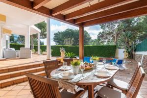 an outdoor patio with a wooden table and chairs at Villa Moll Moll in Cala Blanca