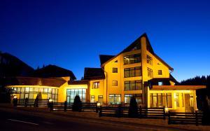a large yellow building with windows at night at Denisa Boutique in Poiana Brasov
