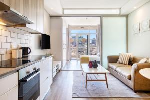 kuchnia i salon z kanapą i stołem w obiekcie Backup-Powered Trendy City Balcony Apartment w Kapsztadzie
