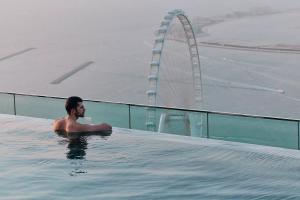 a man in a swimming pool with a ferris wheel in the background at Westminster JBR in Dubai