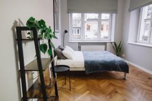 - une chambre avec un lit et une plante dans l'établissement Warsaw Concierge Flat6 Hoza, à Varsovie