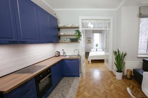 a kitchen with blue cabinets and a living room at Warsaw Concierge Flat6 Hoza in Warsaw