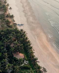 einen Luftblick auf einen Strand mit Palmen und einem Boot in der Unterkunft Planet Hollywood Beach Resort Goa in Utorda