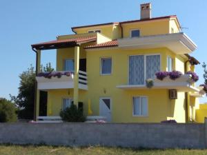 une maison jaune avec des fleurs devant elle dans l'établissement Villa Kamelija, à Fažana