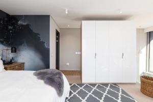 Un dormitorio con una cama blanca con una pared de acento gris en Always-Power Trendy De Waterkant Loft en Ciudad del Cabo