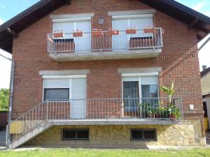a red brick building with balconies and plants on it at OPG Vuk Sobe bed&breakfast "Čarobni snovi" in Darda