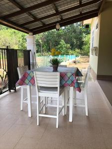 une table et des chaises assises sur une terrasse couverte avec une table et un sidx dans l'établissement afza homestay Bonda Bukit Besi, à Kampong Kuala Talam