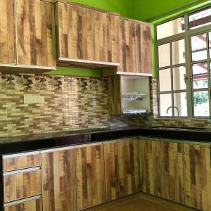 une cuisine avec des placards en bois et une fenêtre dans l'établissement afza homestay Bonda Bukit Besi, à Kampong Kuala Talam