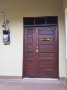 une grande porte en bois avec un panneau. dans l'établissement afza homestay Bonda Bukit Besi, à Kampong Kuala Talam