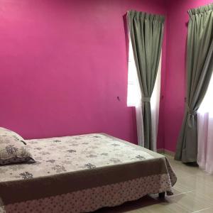 a pink bedroom with a bed and a window at afza homestay Bonda Bukit Besi in Kampong Kuala Talam