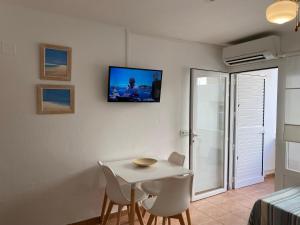 a room with a table and chairs and a tv on the wall at MARINE APARTMENT in Es Pujols