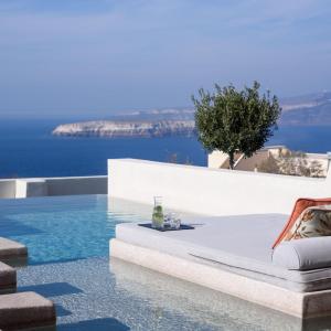 una piscina con un letto e un bicchiere di vino di Potnia Theron Suites ad Akrotírion