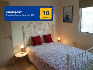 Un dormitorio con una cama con almohadas rojas y una ventana en Larnaca Xylophagou 2-bedroom apartment with a shaded terrace en Xylophaghou