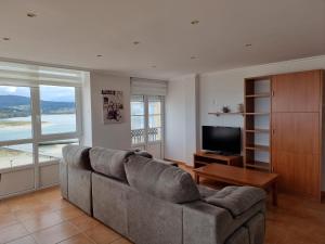 a living room with a couch and a television at Dúplex 4 dormitorios en Playa Rapadoira in Foz