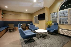 una sala de espera con sillas azules y una mesa en Microtel Inn and Suites Pecos, en Pecos