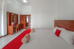 een slaapkamer met een groot wit bed met rode kussens bij RedDoorz Syariah at Abemoch Kampkey in Tobadi