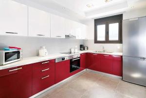 a kitchen with red cabinets and a stainless steel refrigerator at Tsampikos in Gennadi