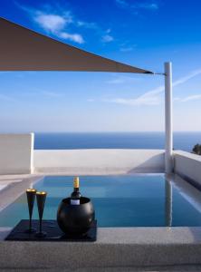 a pool with two candles and two wine glasses at Potnia Theron Suites in Akrotiri +169 photos