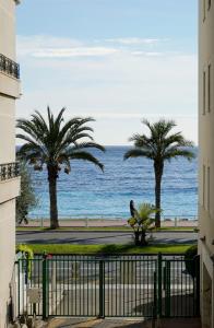 a view of the ocean and palm trees from a building at Cozy studio with a sea view in Nice