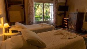 um quarto de hotel com duas camas e uma janela em Aardvark Inn Pousada em Gramado