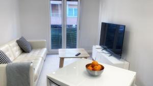 una sala de estar con TV y una mesa con un tazón de naranjas. en Caminando al Guggenheim by Urban Hosts, en Bilbao