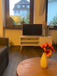 uma sala de estar com televisão e um vaso com flores em Ferienwohnung Bienengarten em Bingen am Rhein