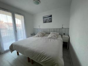 a white bedroom with a large bed and a window at Appartement Les Pieds dans l'eau in Collioure