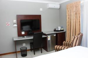 a hotel room with a desk with a television and chairs at Vahlavi Lodge in Giyani